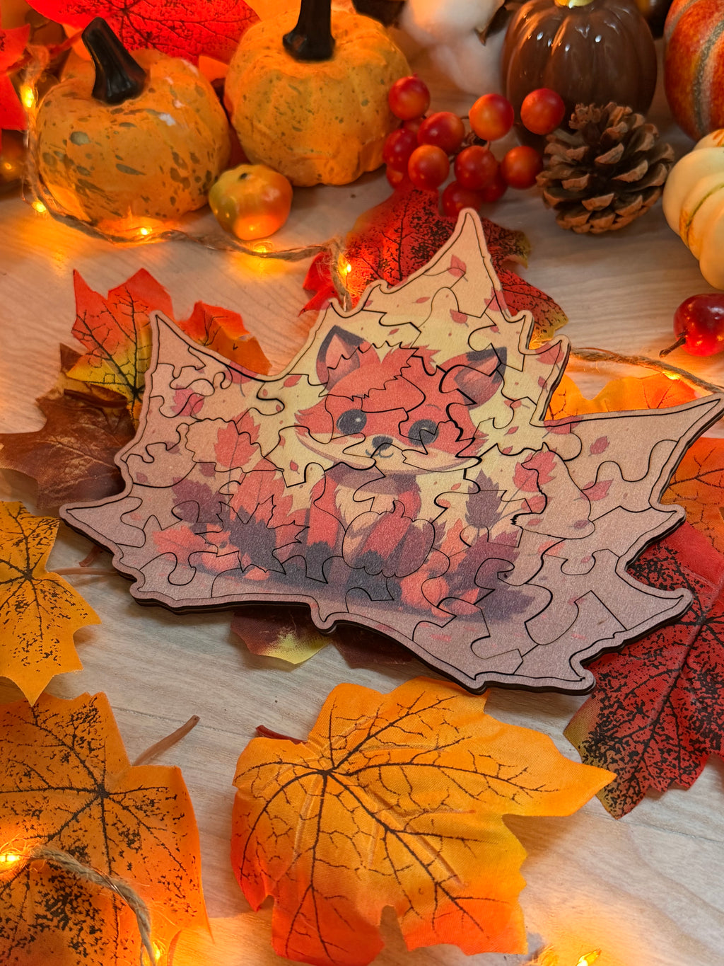 Puzzle en bois de tilleul en forme de feuille d'érable gravée au laser avec un renard, posé sur des feuilles d'automne et des citrouilles - L'Atelier du Moulin