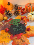 Plaque chaudron de sorcière "Hocus Pocus" en bois gravé et découpé au laser, entourée de citrouilles, pommes de pin et feuilles d'automne - L'Atelier du Moulin