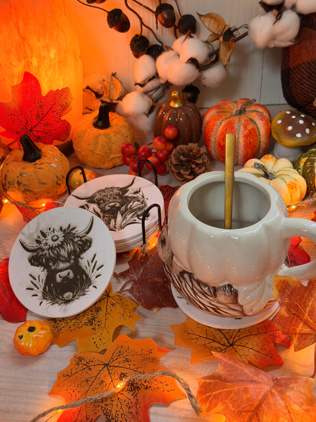 Sous-verres en MDF effet marbre gravés au laser d'une tête de vache Highland, présentés dans un décor d'automne avec citrouilles et feuilles - L'Atelier du Moulin