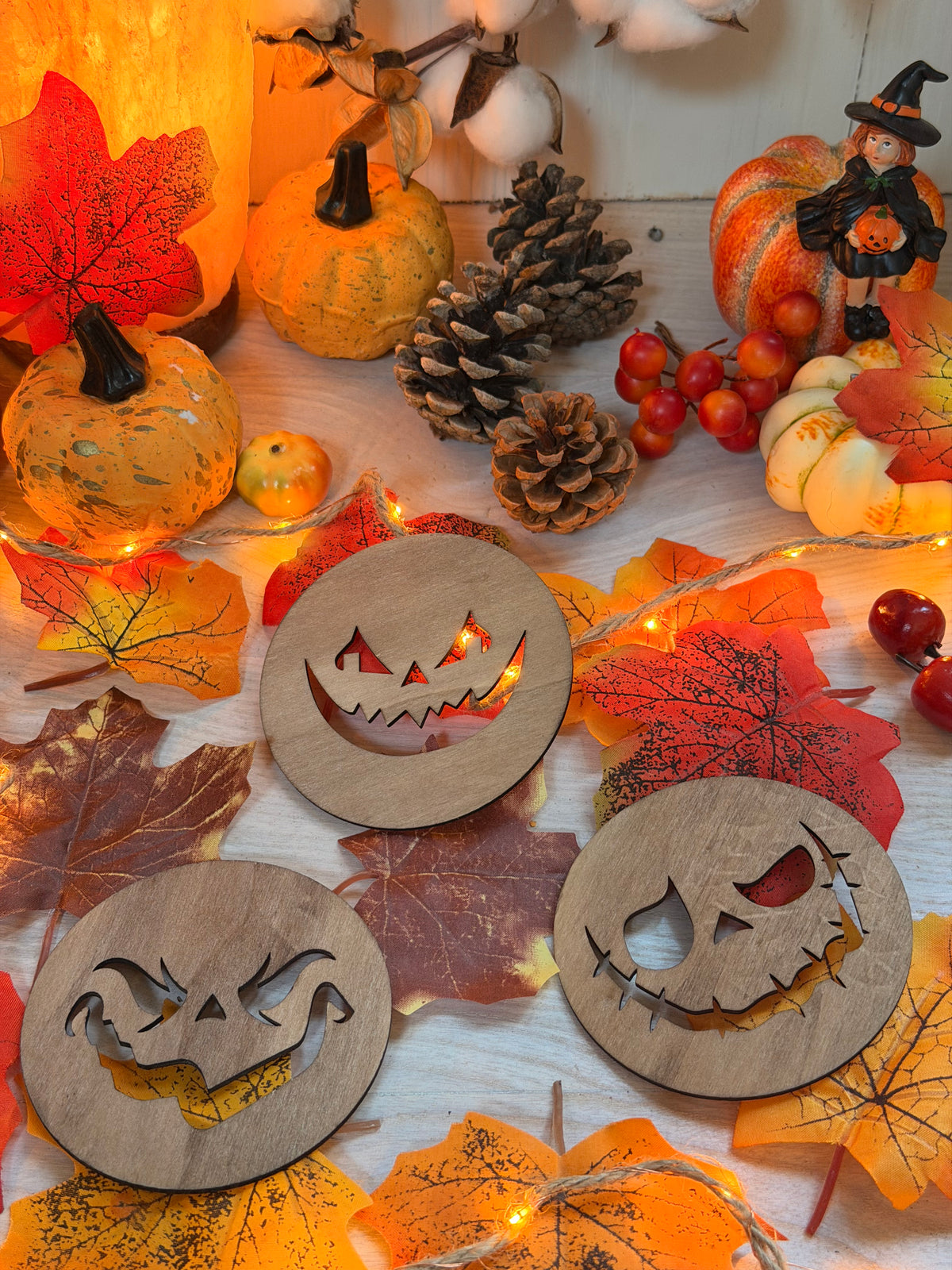 Lot de 3 dessous de verre "Sourires Nocturnes" en bois ajouré, visages de citrouilles Halloween découpés au laser, posés sur des feuilles d'automne - L'Atelier du Moulin