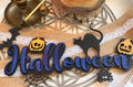 Plaque décorative "Halloween" en bois peint violet et bleu nuit, avec citrouilles, chat noir, chauve-souris, araignée et toile - L'Atelier du Moulin