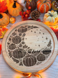 Lune d'Automne, plateau rond en bois gravé au laser d'un croissant de lune orné de citrouilles et de feuillage, entouré de citrouilles décoratives et guirlande lumineuse - L'Atelier du Moulin