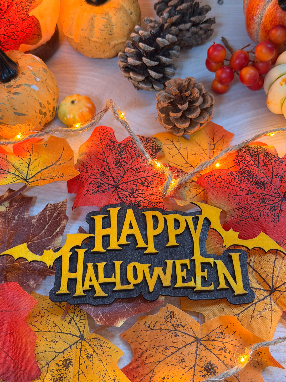 Enseigne "Happy Halloween" en bois gravé et découpé au laser avec chauves-souris, effet relief noir et orange, entourée de citrouilles et feuilles d'automne - L'Atelier du Moulin