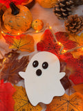 Le P'tit Frisson, petit fantôme en bois blanc découpé au laser, posé parmi citrouille, pommes de pin et feuilles d'automne - L'Atelier du Moulin