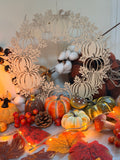 Couronne des récoltes d'Automne, couronne en bois clair découpée au laser en silhouettes de citrouilles, ornée de coton, posée parmi mini citrouilles, feuilles d'automne et guirlande lumineuse - L'Atelier du Moulin